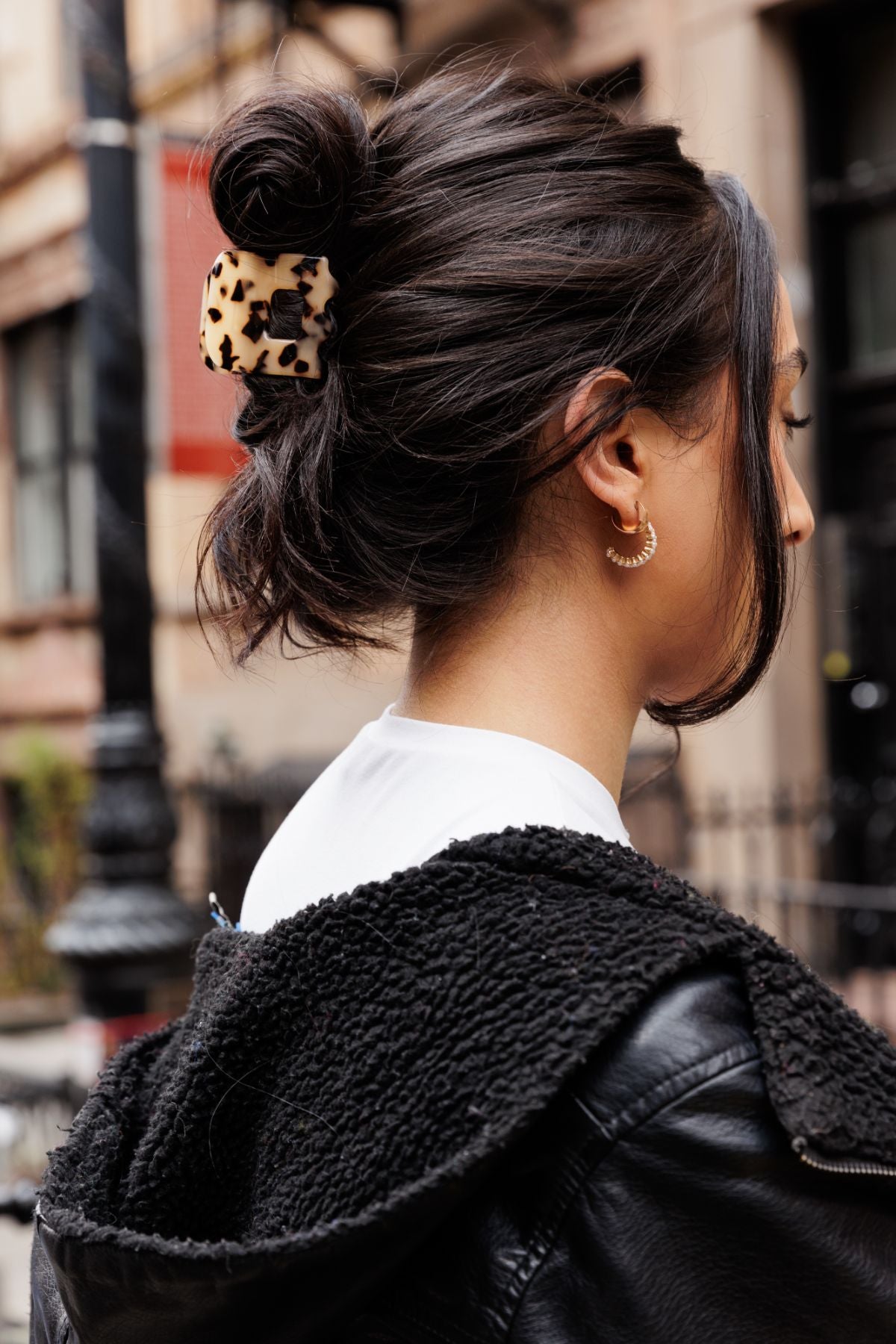 Brunette woman with black leather jacket wears an OG FiZZY claw clip showcasing one of many hair accessories for wholesale