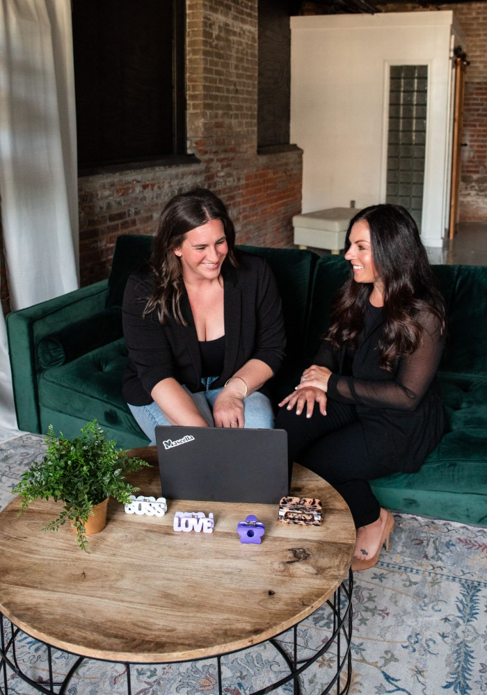 Two women founders of FiZZY, a brand offering patented hair claws for women, laughing together on a green couch