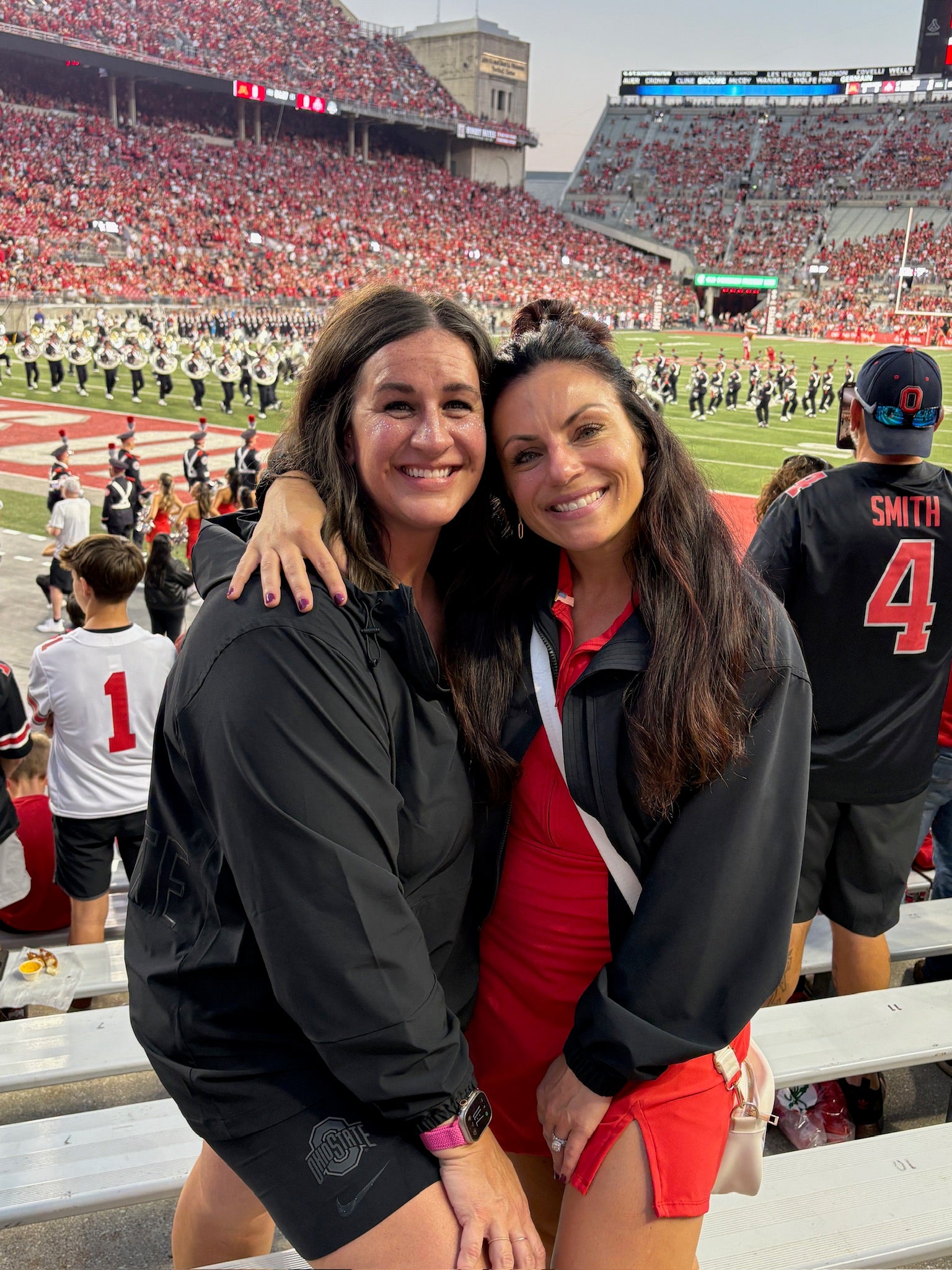 Two women founders of FiZZY posing for a photo at an OSU sports event with a crowd and field in the background.