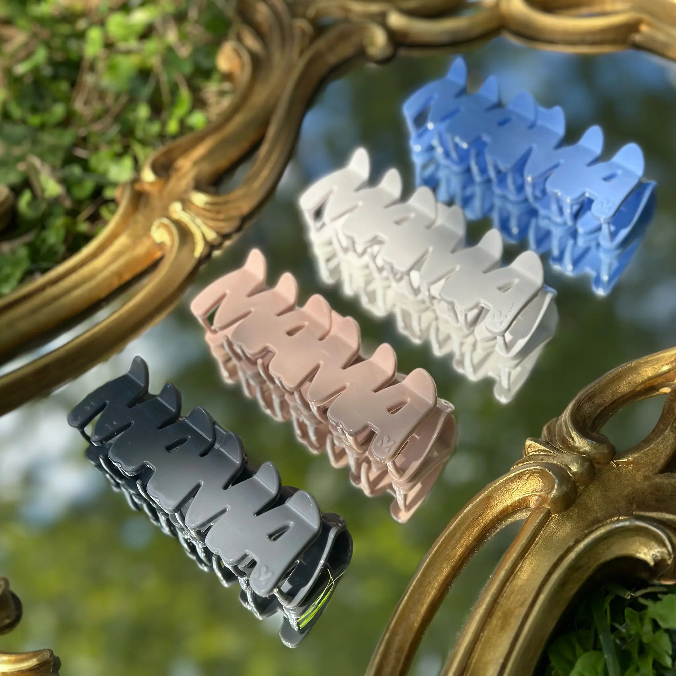 FiZZY patented MAMA hair claw clips in different colors lined up in a row on top of a golden mirror