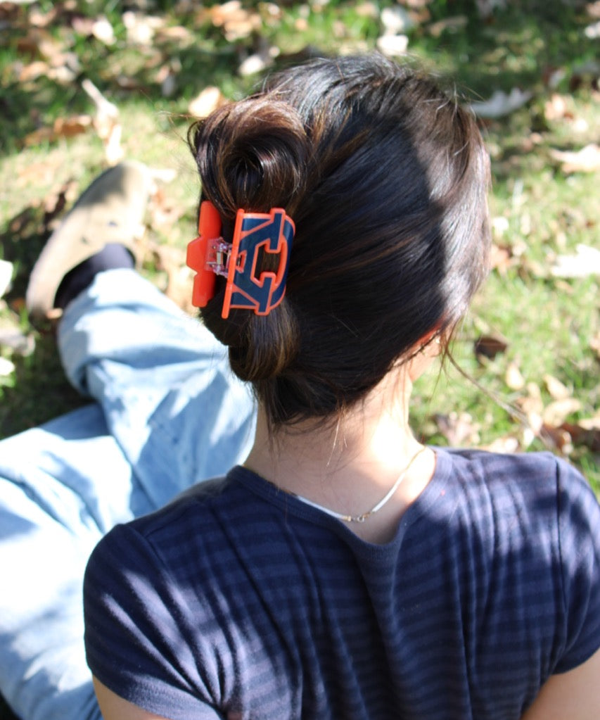 Person with a bun wearing an orange and blue collegiate Auburn hair clip outdoors