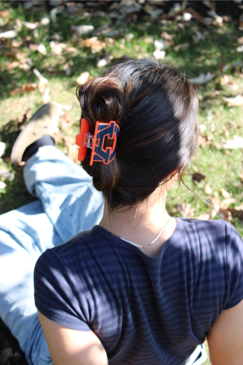 Person with a bun wearing an orange and blue collegiate Auburn hair clip outdoors